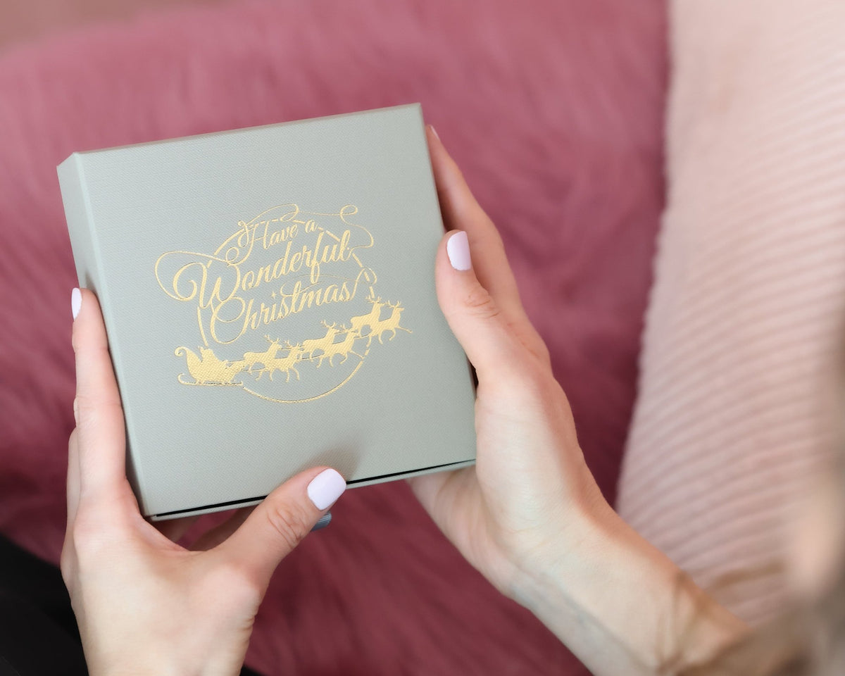 Hände halten den Schmuck-Adventskalender in seiner Geschenkbox